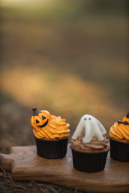 Cute Halloween-themed cupcakes with festive decorations on a wooden platter outdoors.