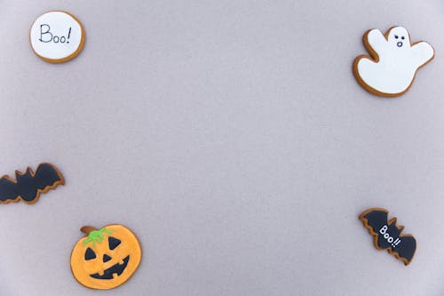 Top view of assorted gingerbread cookies with icing in different Halloween decoration shapes arranged on gray surface as frame