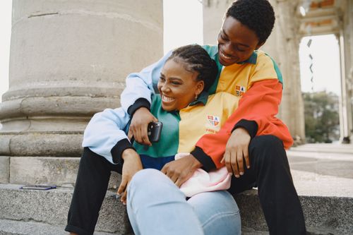 Free A joyful couple wearing colorful jackets sharing a happy moment outdoors on stone steps. Stock Photo