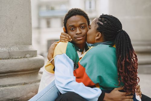 Free A young couple shares an affectionate moment while sitting outdoors. Stock Photo