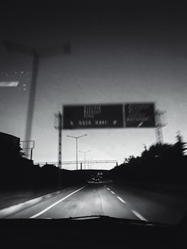 Black and white view of Turkish highway at night with road signs and lanes visible.