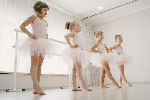 Free Four young girls in tutus practicing ballet dancing indoors, enjoying their ballet class. Stock Photo