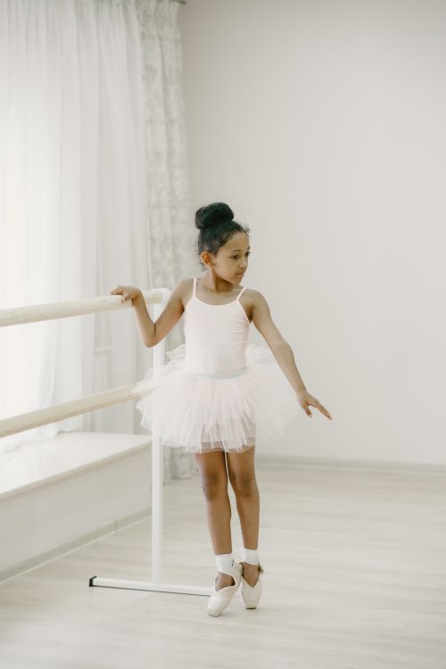 Free A young girl practicing ballet at the barre in a bright dance studio. Stock Photo