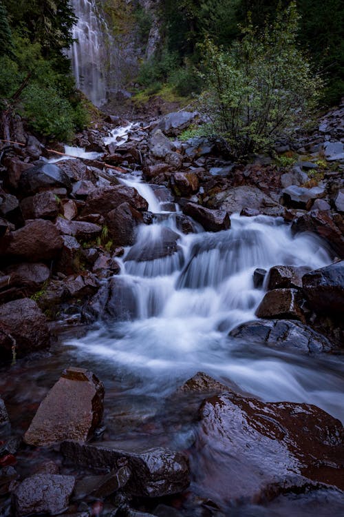 Stream Flowing Through Rocks in Mountains