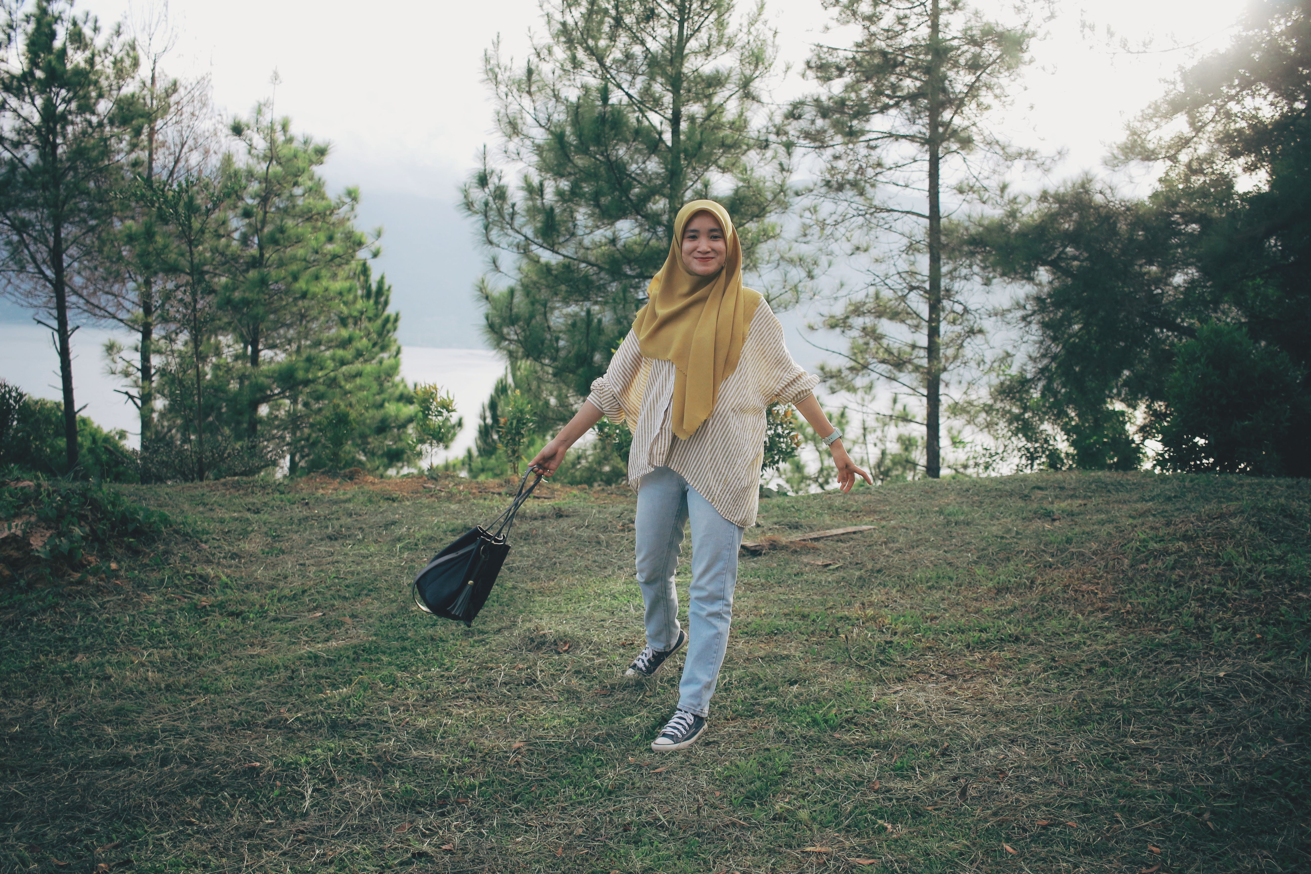 A young woman in a hijab enjoying a walk through a scenic forest landscape.