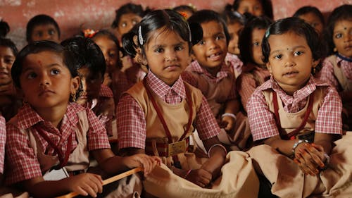 Free Children Sitting on the Ground in the Classroom Stock Photo