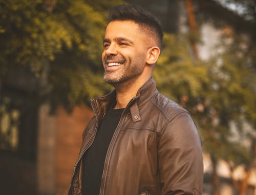 Free Man in Brown Leather Jacket Standing Near Green Trees Stock Photo