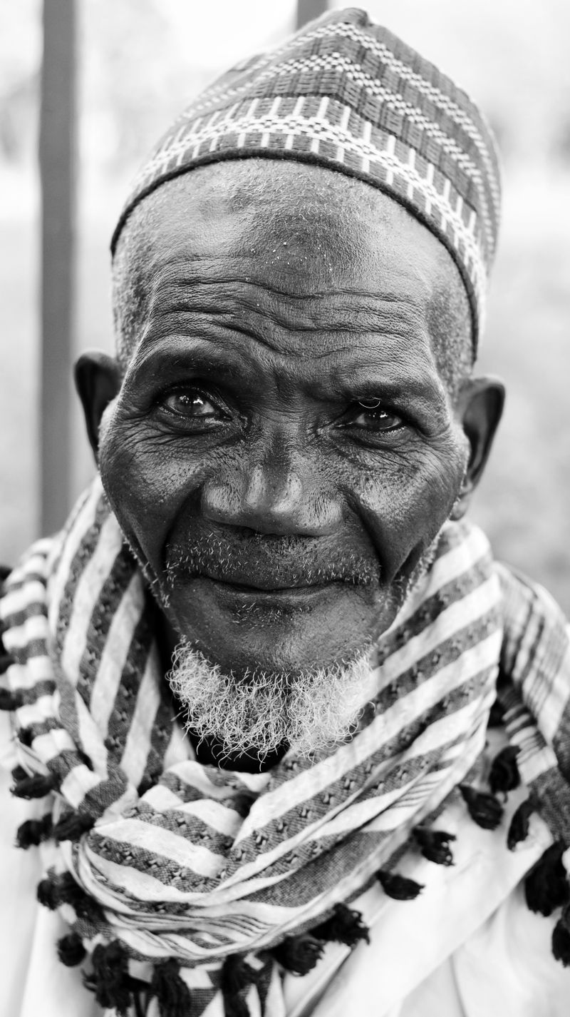 Black-and-white portrait of an older Black man with deeply pigmented, weathered skin, used to illustrate reporting on recognizing shingles on dark skin in adults over 50.