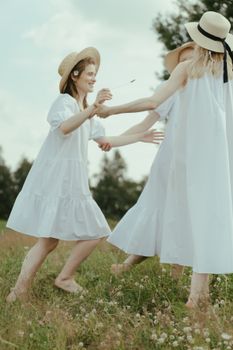 三个女人穿着白色连衣裙，赤着脚，无忧无虑地在草地上享受夏日时光
