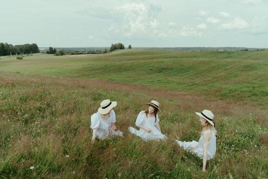 Three Women in White Dress Sitting on Meadow