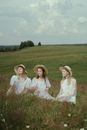 Three Women in White Dress Sitting on Meadow