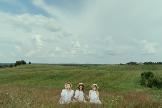 Three Women in White Dress Sitting on Meadow