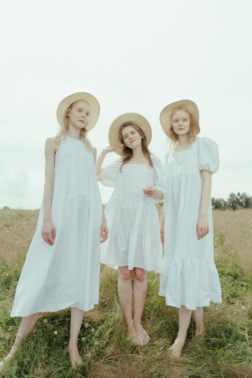 Three Women in White Dress Standing on the Grass