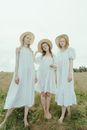 Three Women in White Dress Standing on the Grass