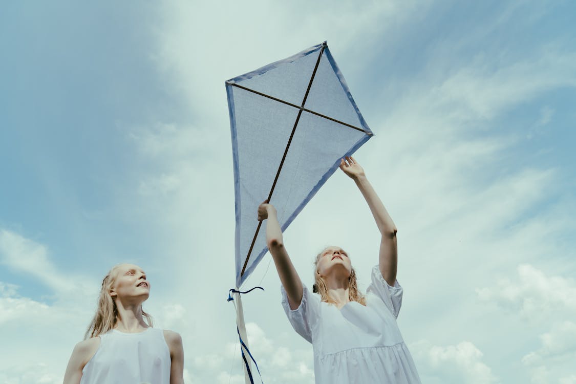 Low-Angle Shot of Women in White Dress Playing With Kite
