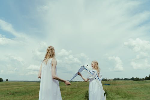 Women in White Dress Playing With Kite on the Grass Field