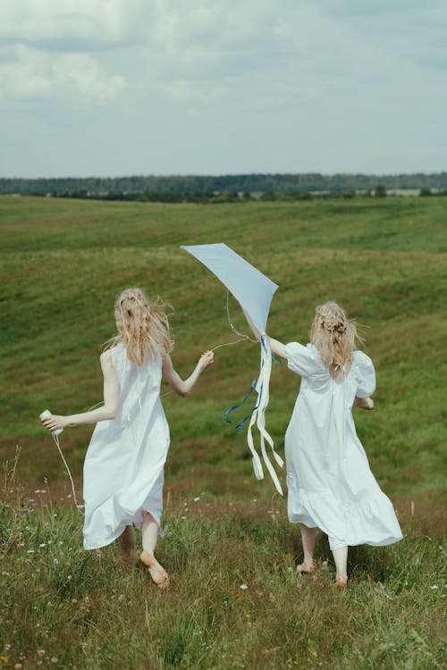 Women in White Dress Playing With Kite on the Grass Field