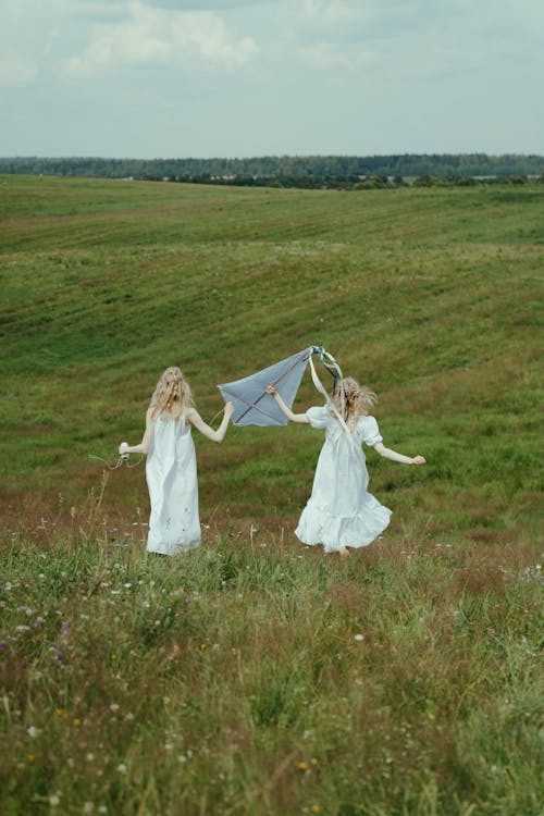 Women in White Dress Playing With Kite on the Grass Field