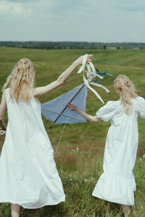 Women in White Dress Playing With Kite on the Grass Field