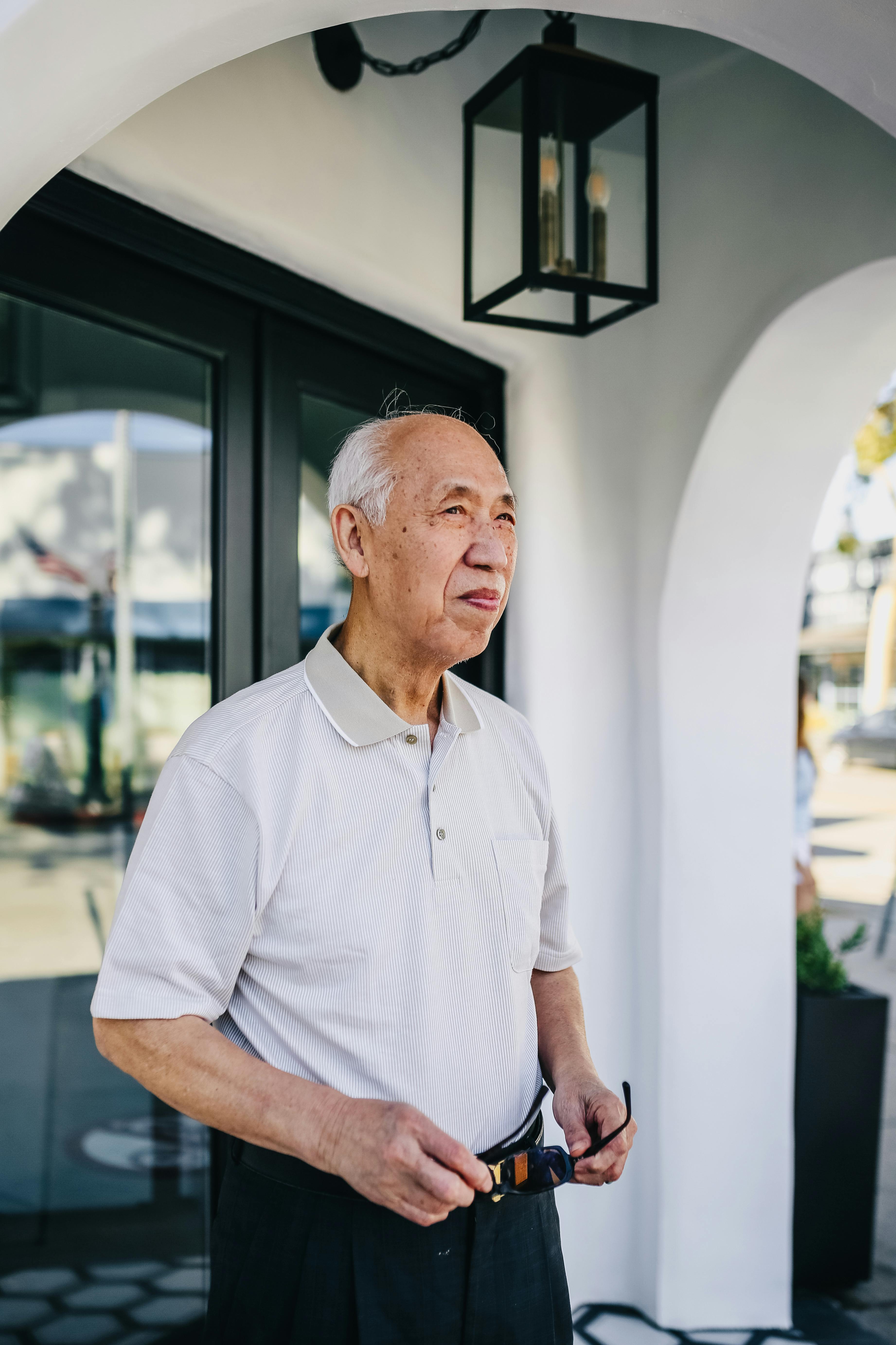 man in white polo shirt standing outside holding his sunglasses