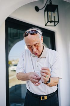 大楼外，一名戴着太阳镜的老人正在调整手表