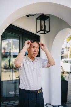 一名男子在现代建筑外调整太阳镜，享受阳光明媚的一天