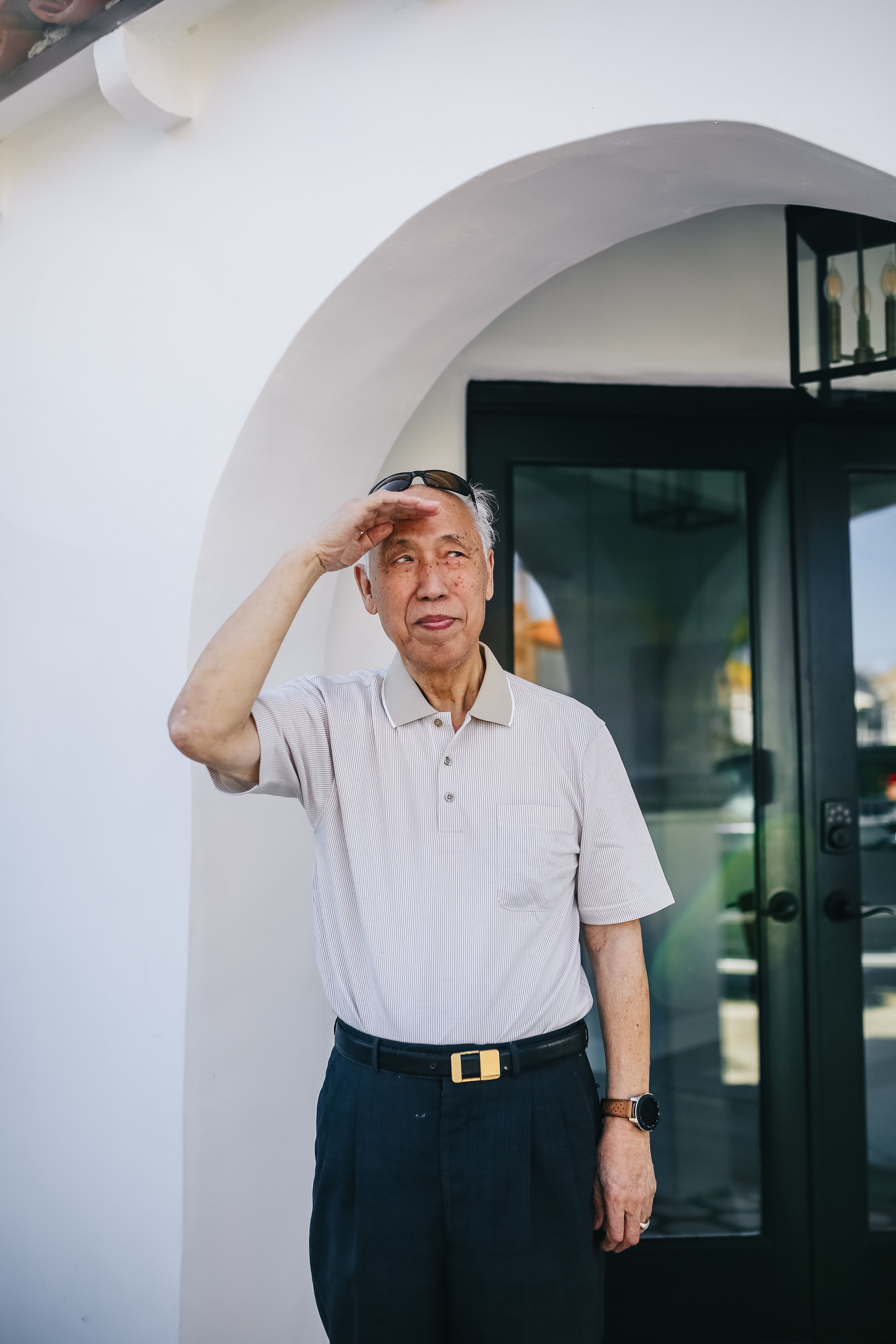 一位年长男子站在户外入口处，望着镜头