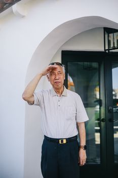 一位年长男子站在户外入口处，望着镜头