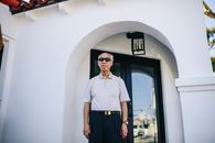 一名戴着太阳镜的高级男子站在现代住宅入口外