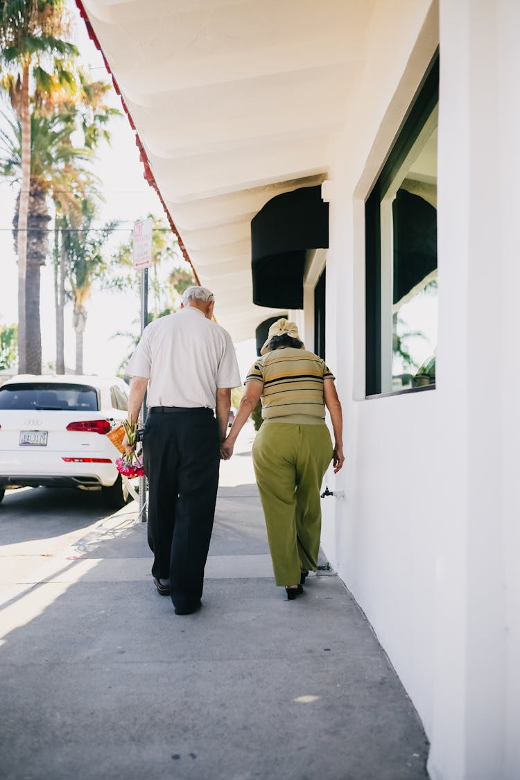 Elderly Couple Walking With Holding Hands On Sidewalk
