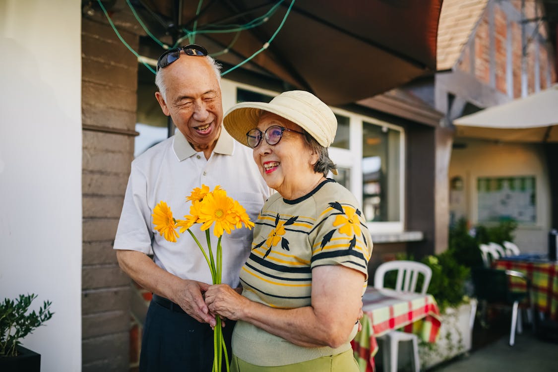 Free Elderly Couple Holding Bouquet of Flowers while Holding Hands Stock Photo