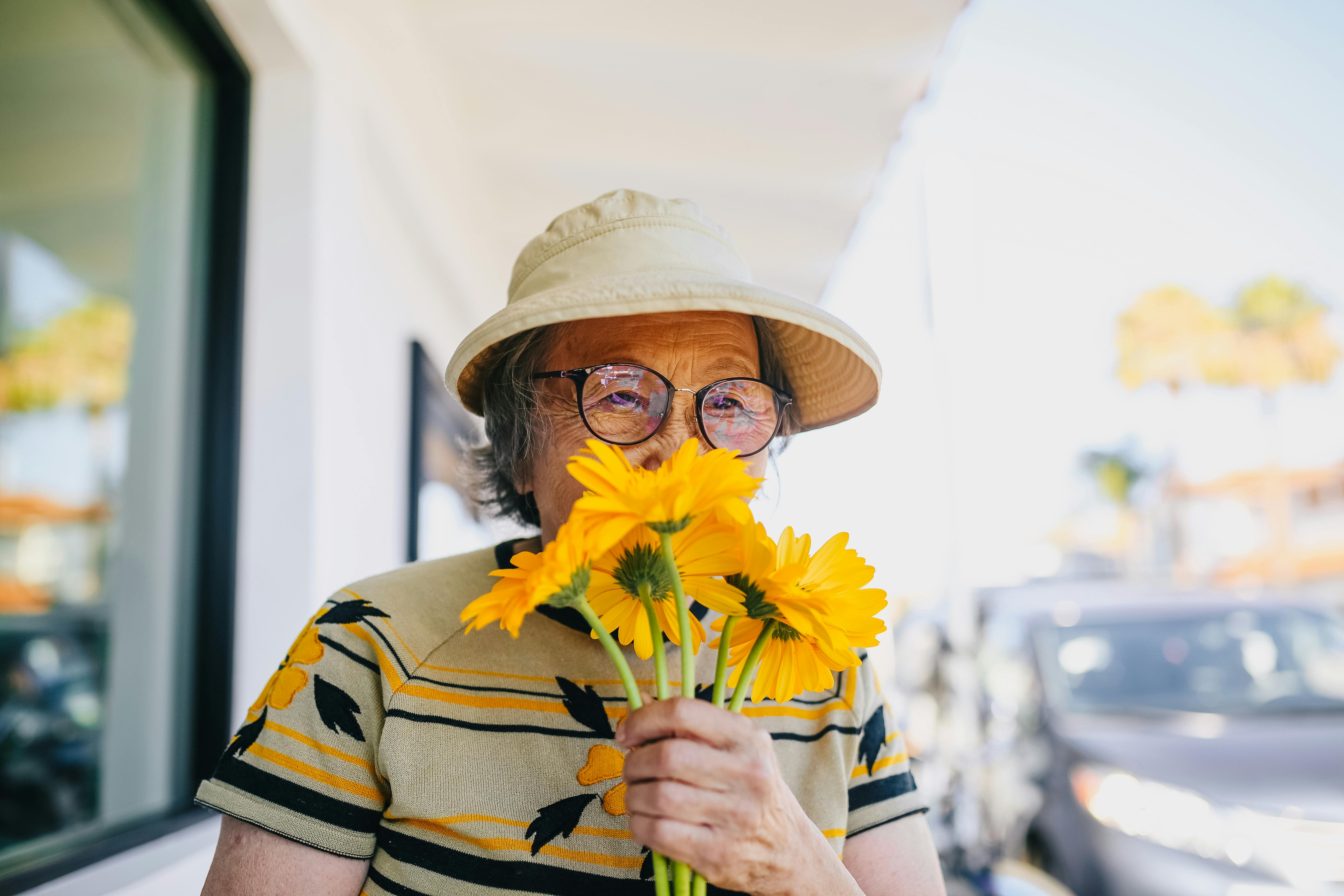 elderly woman smelling yellow flowers