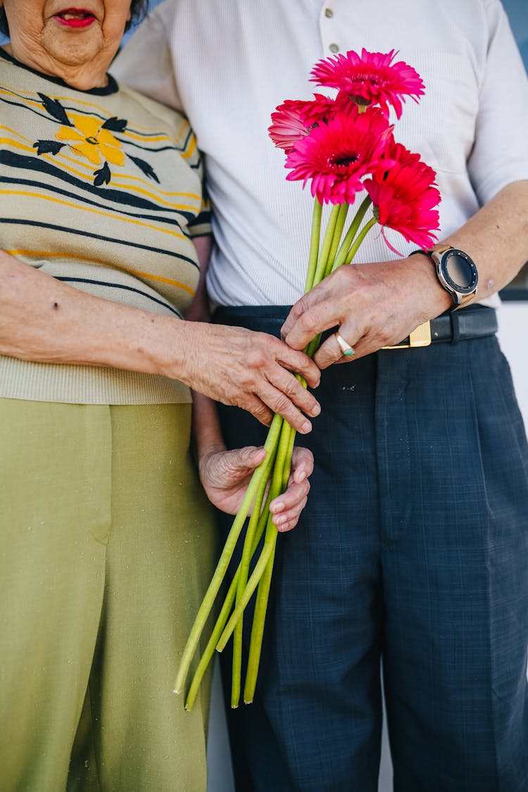 Elderly Couple Holding Red Flowers