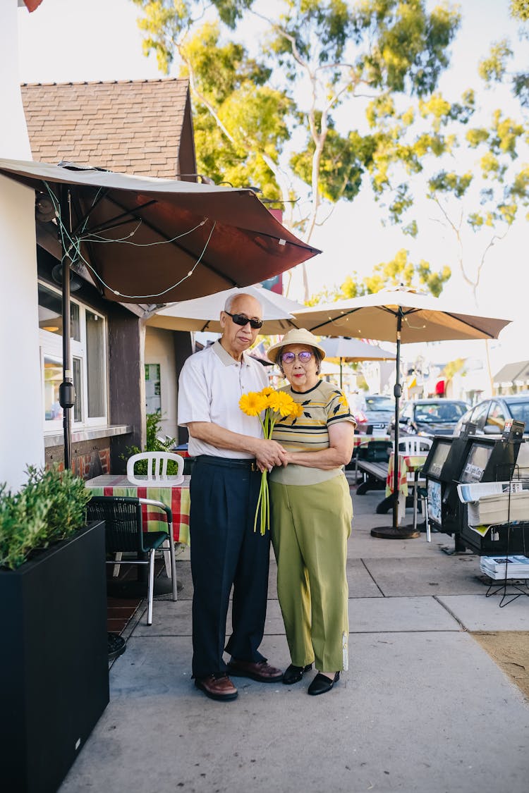 Elderly Couple Holding Bouquet Of Flowers While Holding Hands