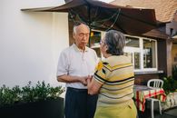 Senior Asian couple holding hands and expressing love and affection in a sunny outdoor setting.
