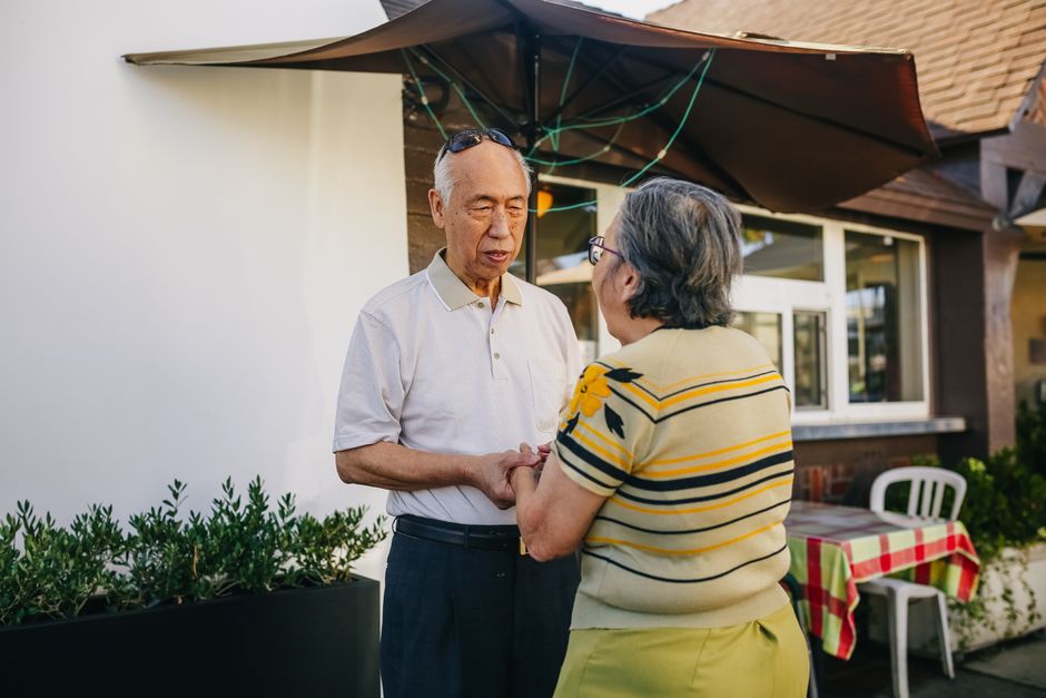 Senior Asian couple holding hands and expressing love and affection in a sunny outdoor setting.