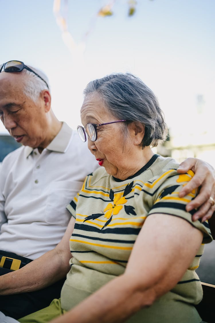 Elderly Couple Sitting On Wooden Bench