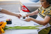 一对老年夫妇在户外咖啡馆里，一边享用咖啡，一边欣赏鲜花，放松身心