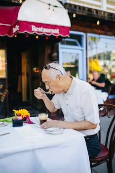 阳光明媚，老人在一家迷人的户外咖啡馆品尝咖啡