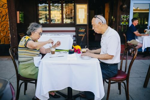 Free Senior Asian couple enjoying coffee outdoors at a street cafe, sharing quality time together. Stock Photo