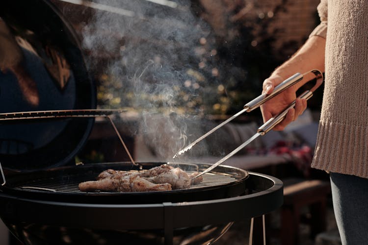 Close-Up Shot Of A Person Grilling Chicken