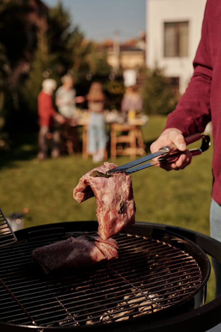 Close-Up Shot Of A Person Grilling Steak