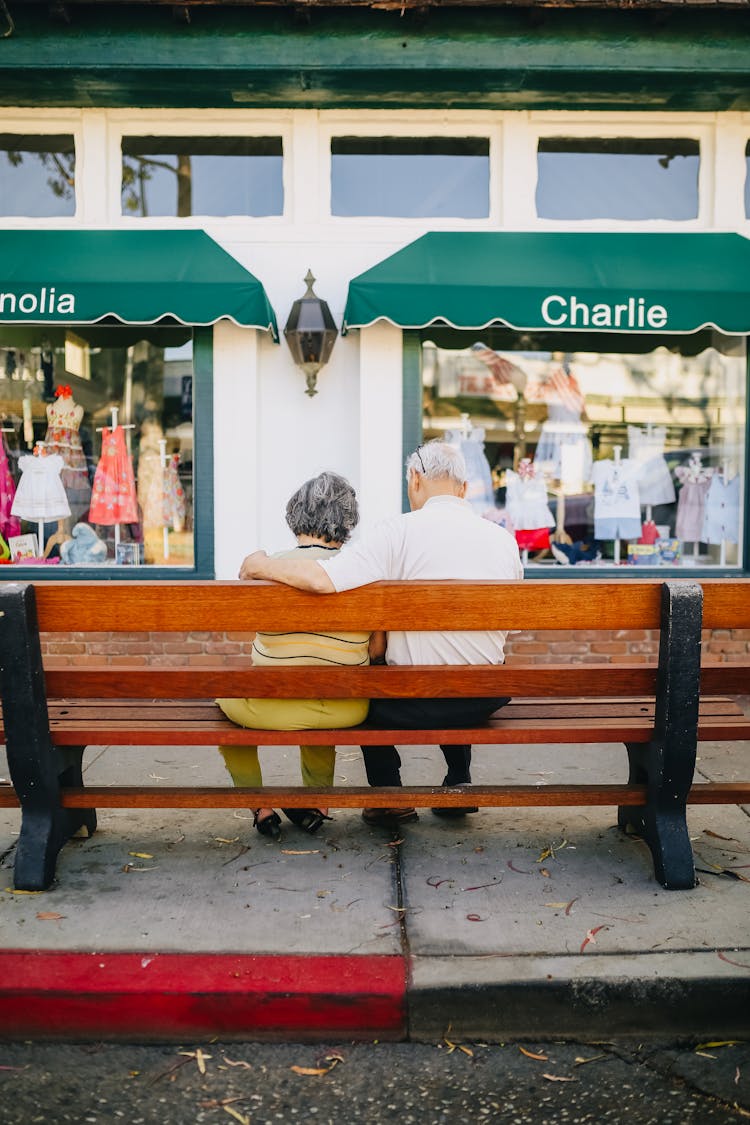 Man And Woman Sitting On Brown Wooden Bench