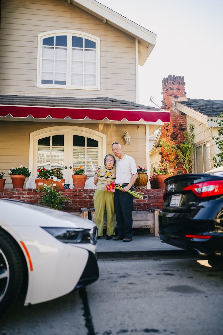 Elderly Couple Standing Outside Their House