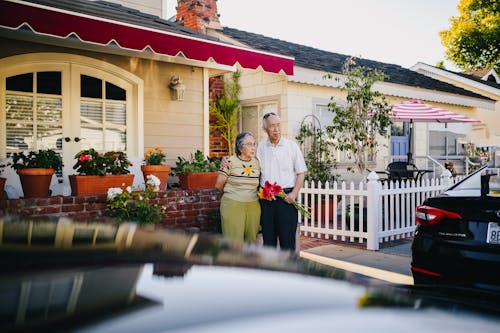 Elderly Couple Standing Outside the House