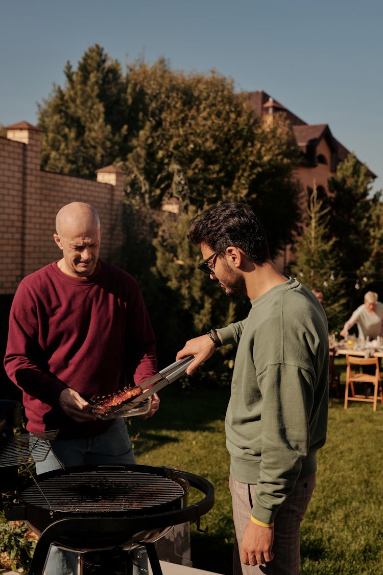 Two Men Grilling Meat Together