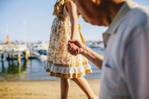 Grandfather Holding His Granddaughter's Hand while Walking