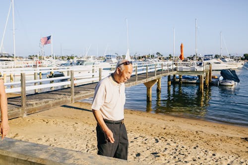 Man in White Crew Neck T-shirt and Black Pants Standing on Beach