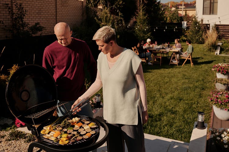 A Couple Grilling Vegetables Together