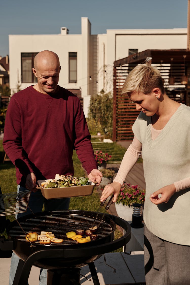 A Couple Grilling Vegetables Together